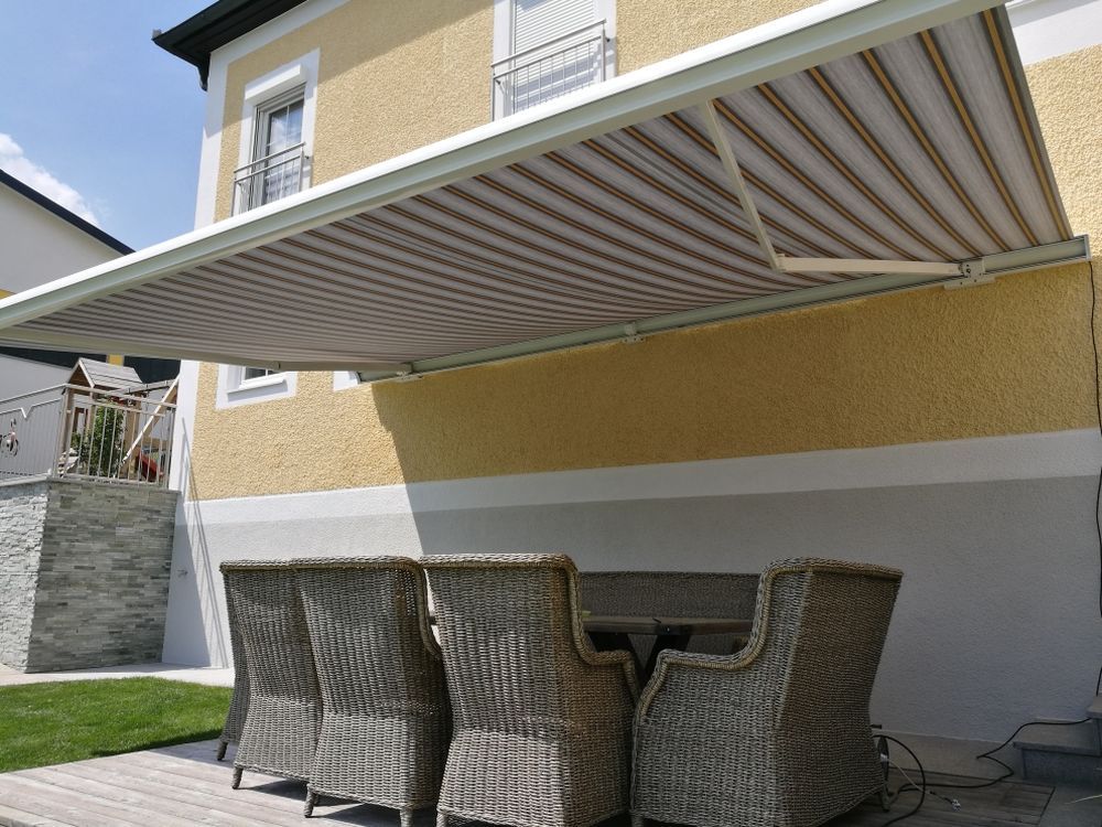 Eine Terrasse mit Tisch und Stühlen unter einer Markise