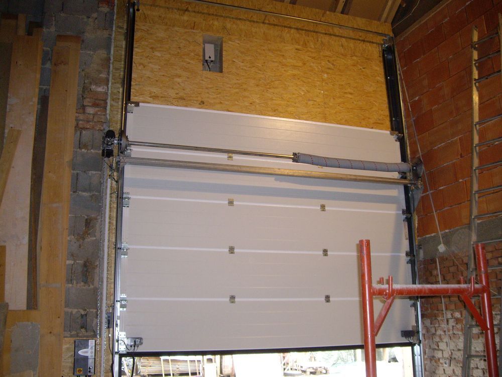 In einem Backsteingebäude steht ein weißes Garagentor offen