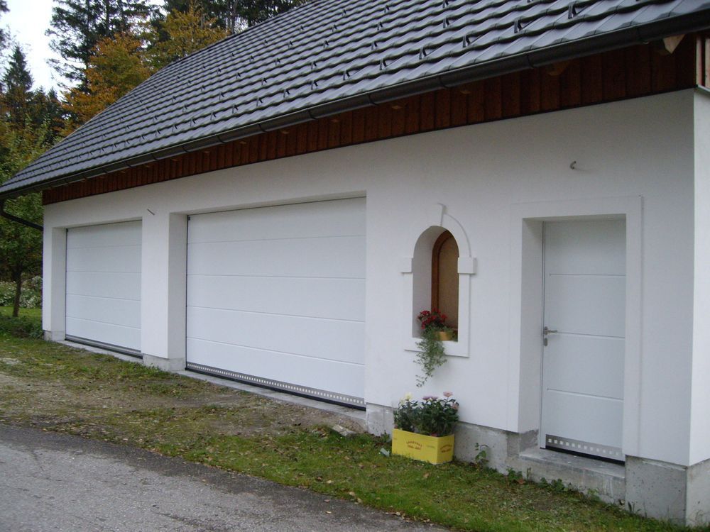 Eine weiße Garage mit grauem Dach und weißen Türen