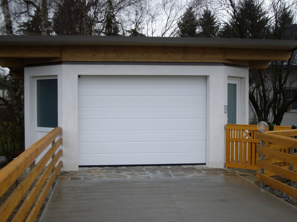 Ein weißes Garagentor mit einem Holzzaun darum