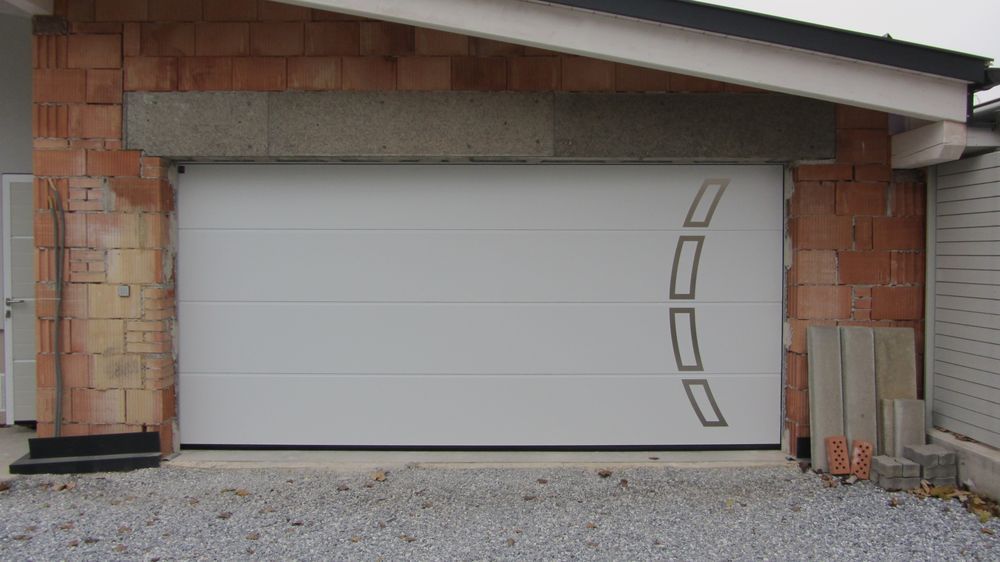 Vor einem Backsteingebäude steht ein weißes Garagentor.