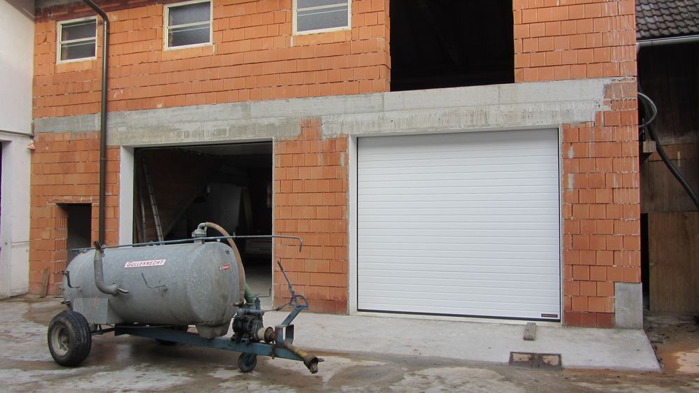 Ein grauer Tank steht vor einem Backsteingebäude