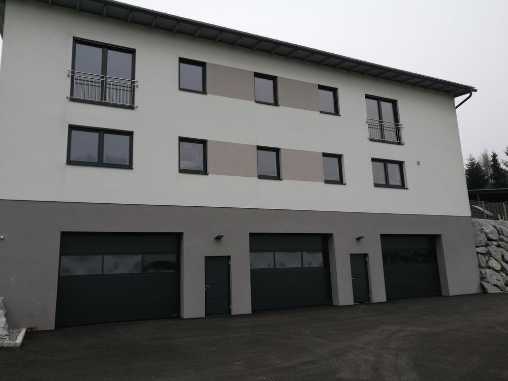 Ein weißes Gebäude mit vielen Fenstern und Garagentoren