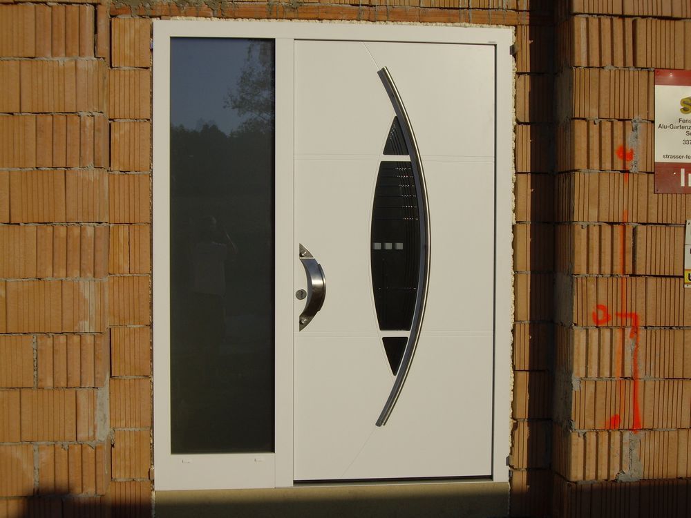 Eine weiße Tür mit einem Edelstahlgriff befindet sich an einer Ziegelwand