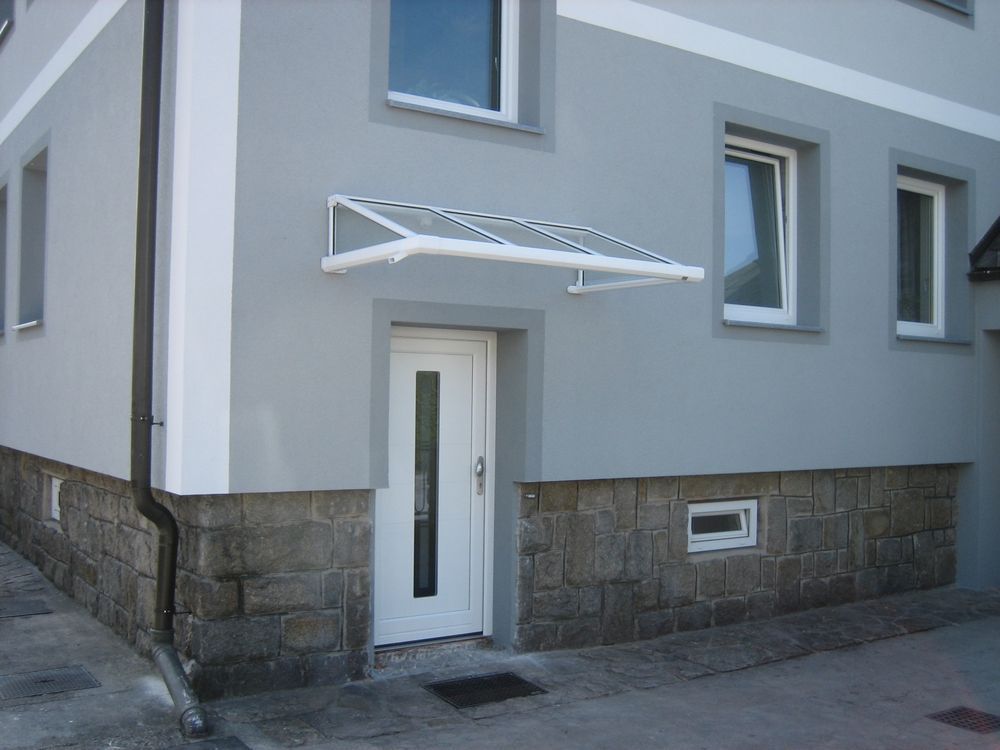 Eine weiße Tür mit einem Vordach darüber befindet sich an der Seite eines Gebäudes