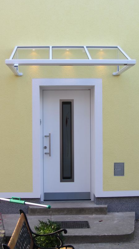 Ein gelbes Gebäude mit einer weißen Tür und einem Vordach darüber