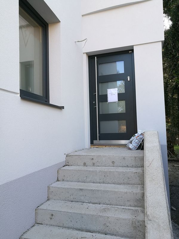 Ein weißes Gebäude mit einer schwarzen Tür und Treppe