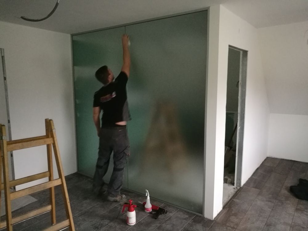 Ein Mann putzt eine Glaswand in einem Raum