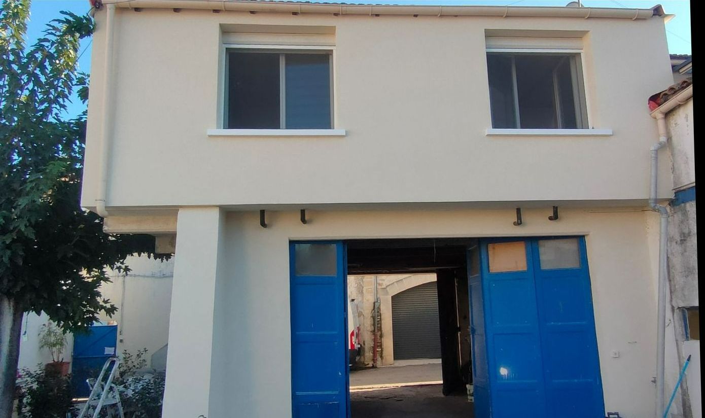 Façade d'une maison après un ravalement avec des portes bleu foncé