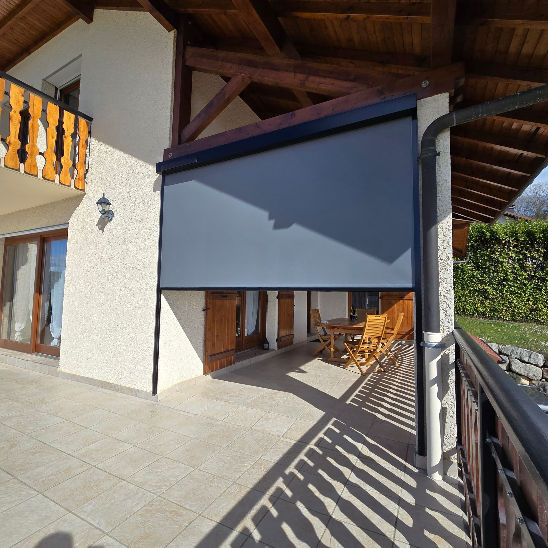 Un auvent gris ombrage un patio avec des meubles et un bâtiment en bois.