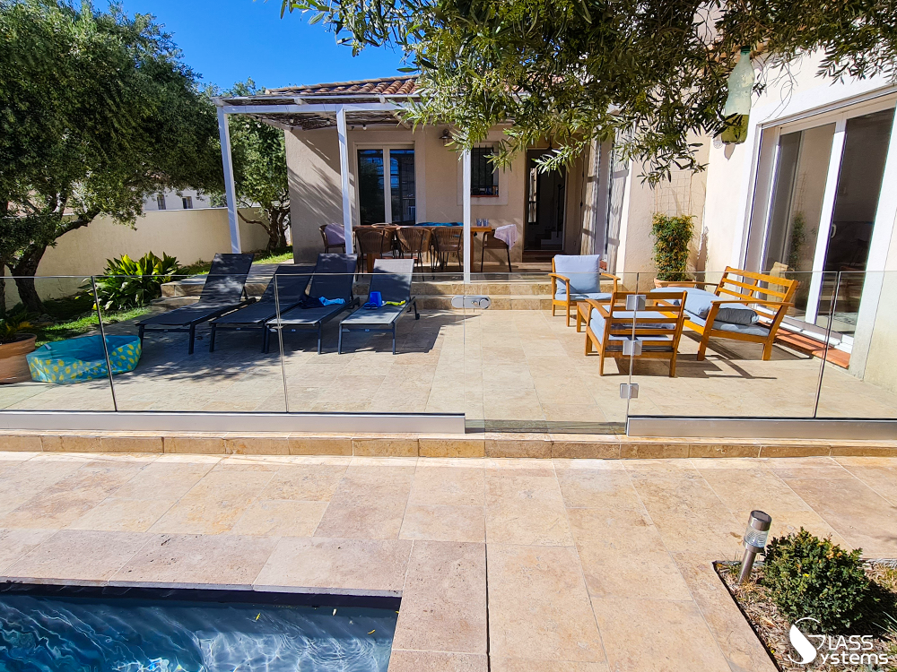 Patio avec sièges, piscine et maison dans un cadre extérieur ensoleillé.