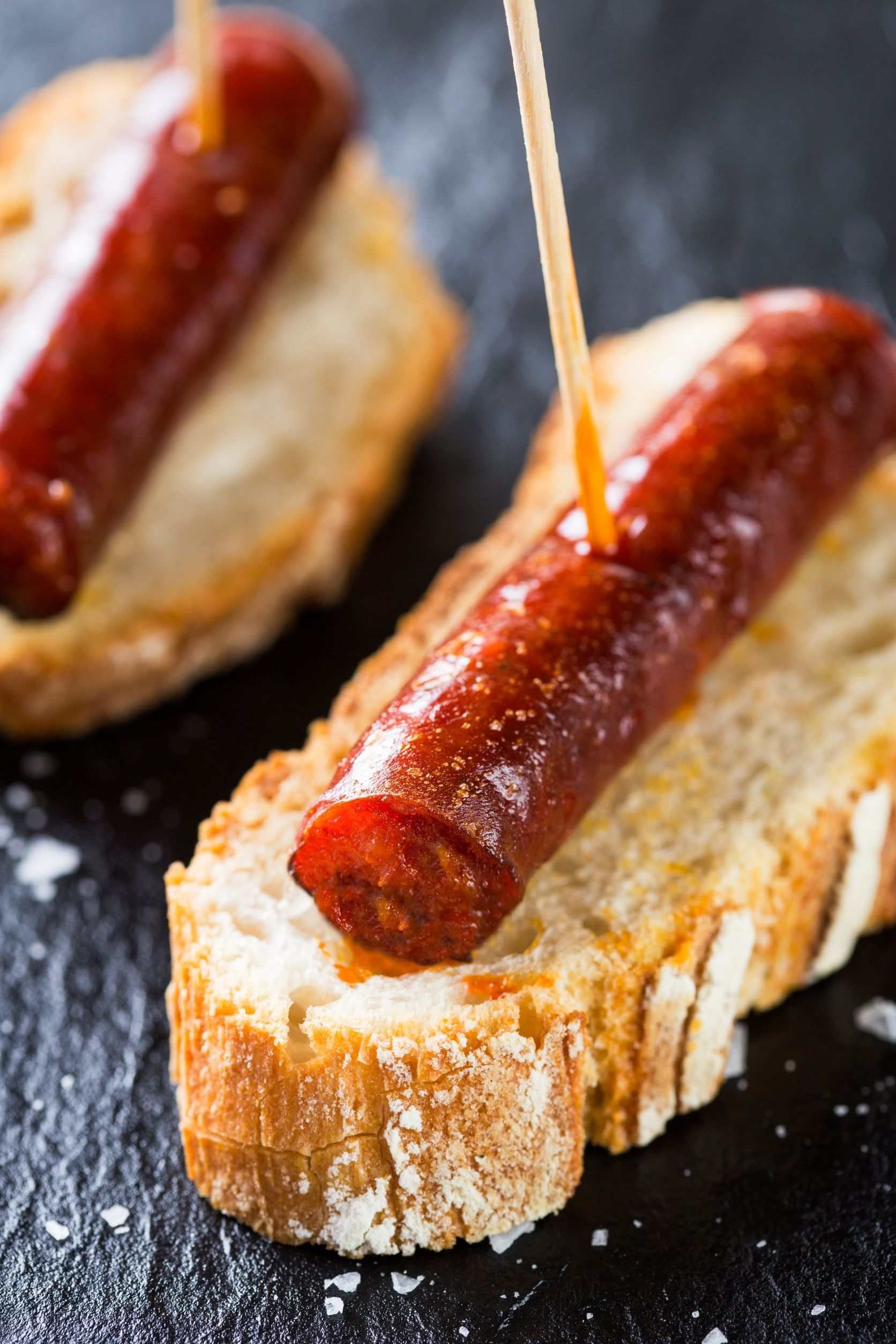 Una salchicha sobresale de un trozo de pan.