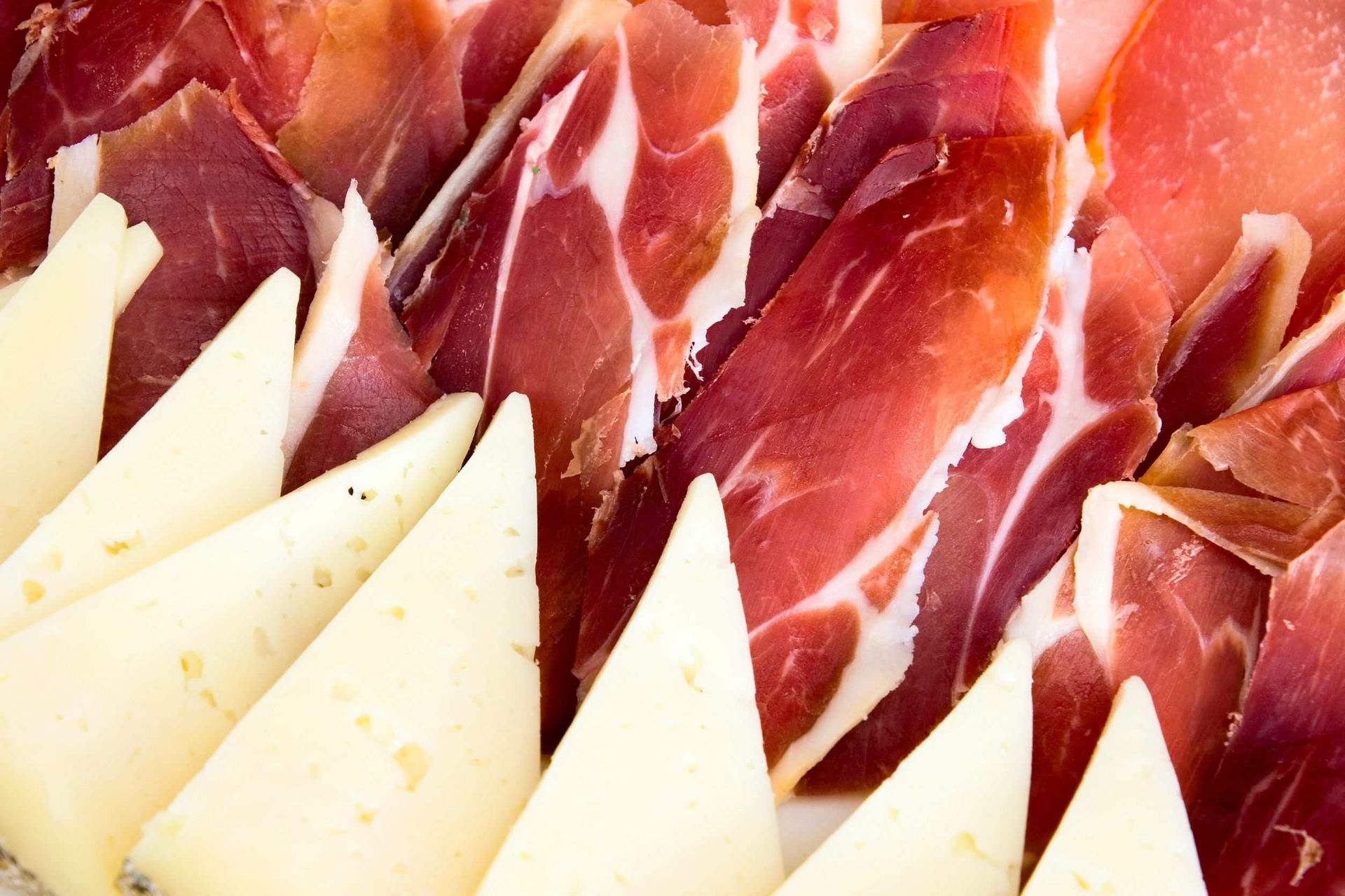 Un primer plano de carne cortada en rodajas y queso en un plato.