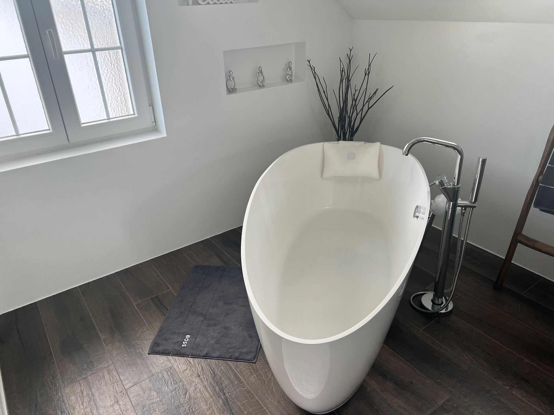 Eine weiße Badewanne steht in einem Badezimmer neben einem Fenster.