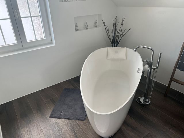 Eine weiße Badewanne steht in einem Badezimmer neben einem Fenster.