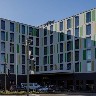 Ein großes Gebäude mit vielen Fenstern und davor geparkten Autos.