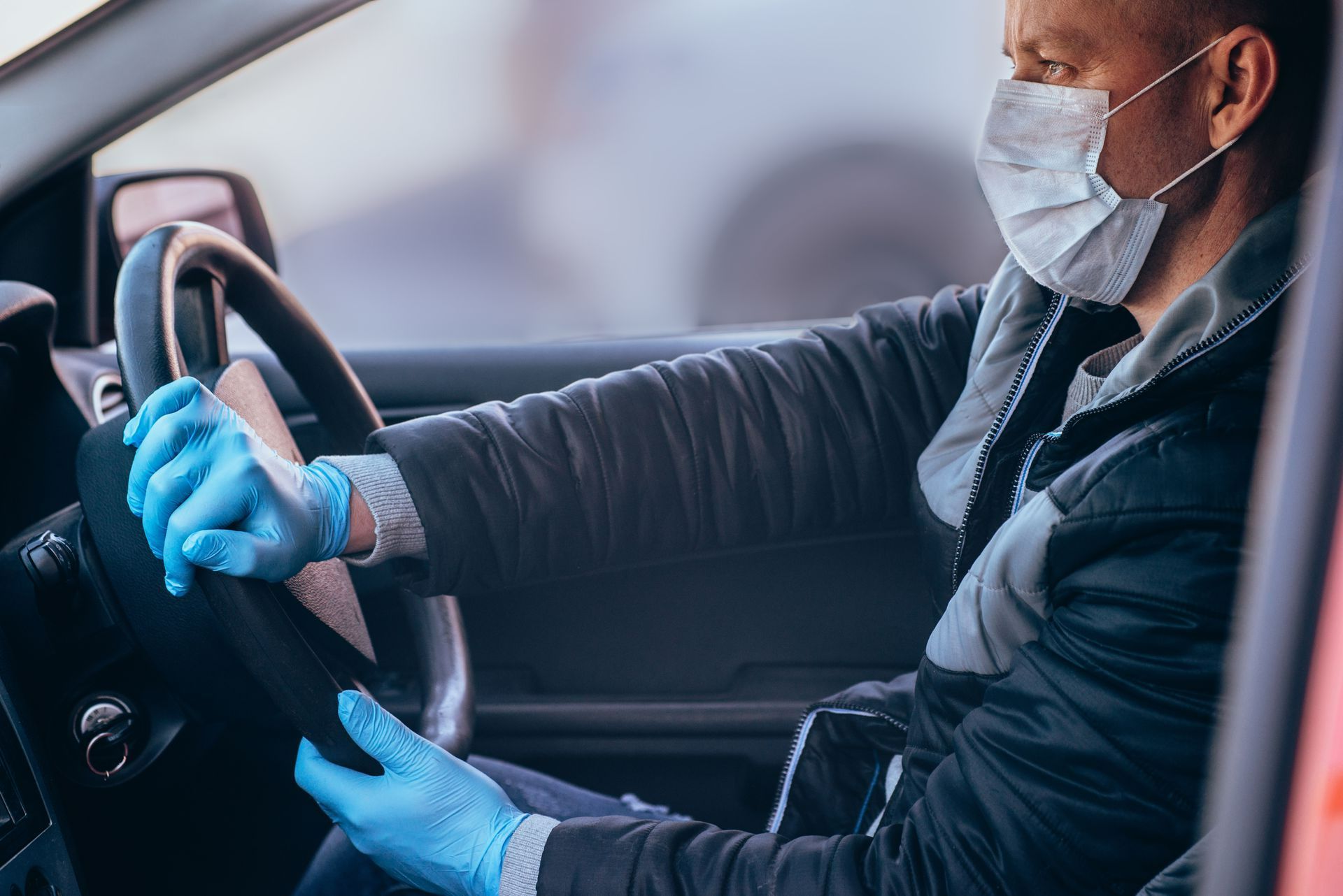 Homme portant des gants et un masque conduit une voiture
