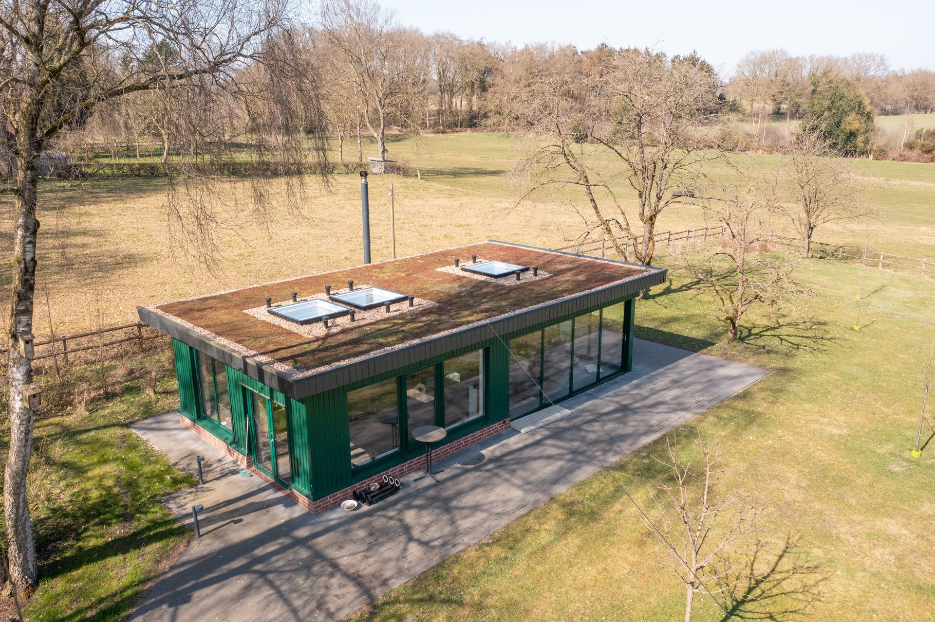 Eine Luftaufnahme eines Gewächshauses mit einem Gründach inmitten eines Feldes.