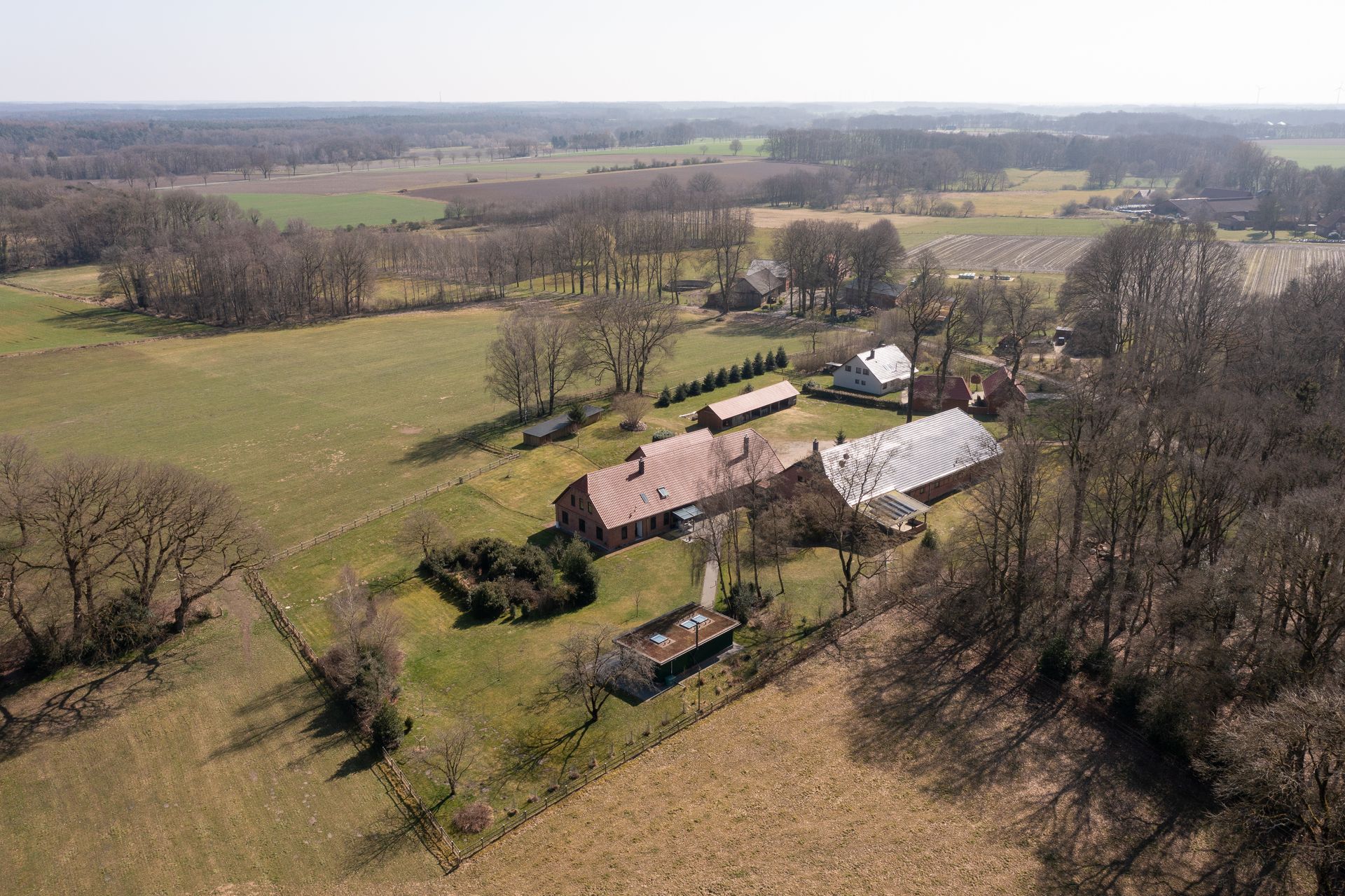 Eine Luftaufnahme einer Farm inmitten eines von Bäumen umgebenen Feldes.