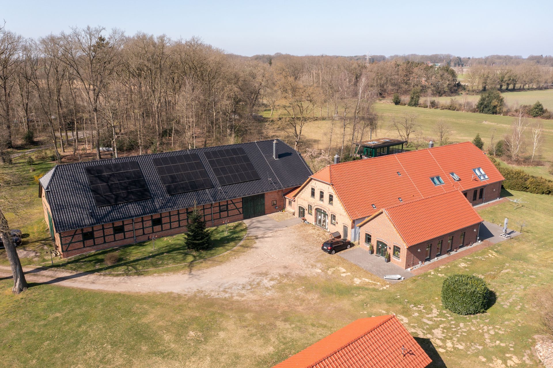 Eine Luftaufnahme eines Bauernhauses mit Solarmodulen auf dem Dach.