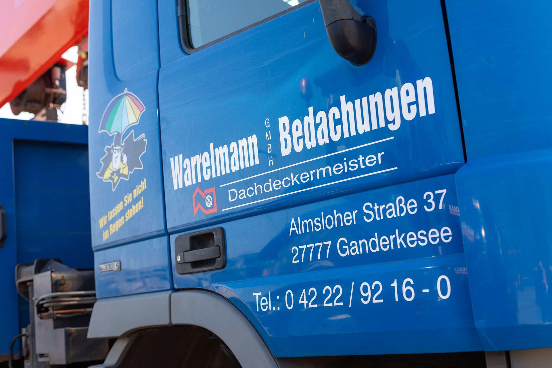 Ein blauer LKW, auf dessen Seite „Warrelmann Bedachungen“ steht