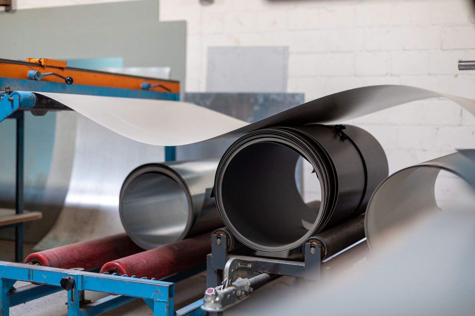 In einer Fabrik liegen mehrere Metallrollen auf einem Förderband.