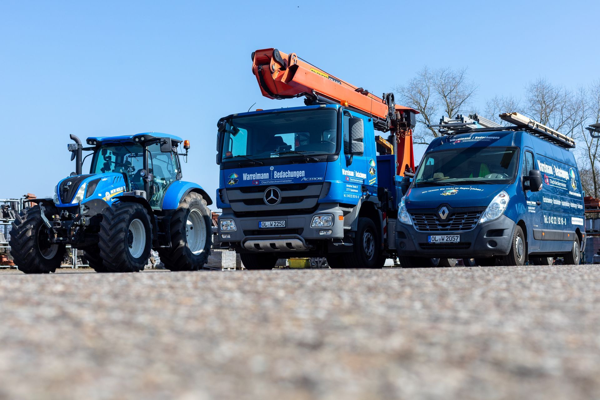Ein Traktor, ein Lastwagen und ein Lieferwagen stehen am Straßenrand.