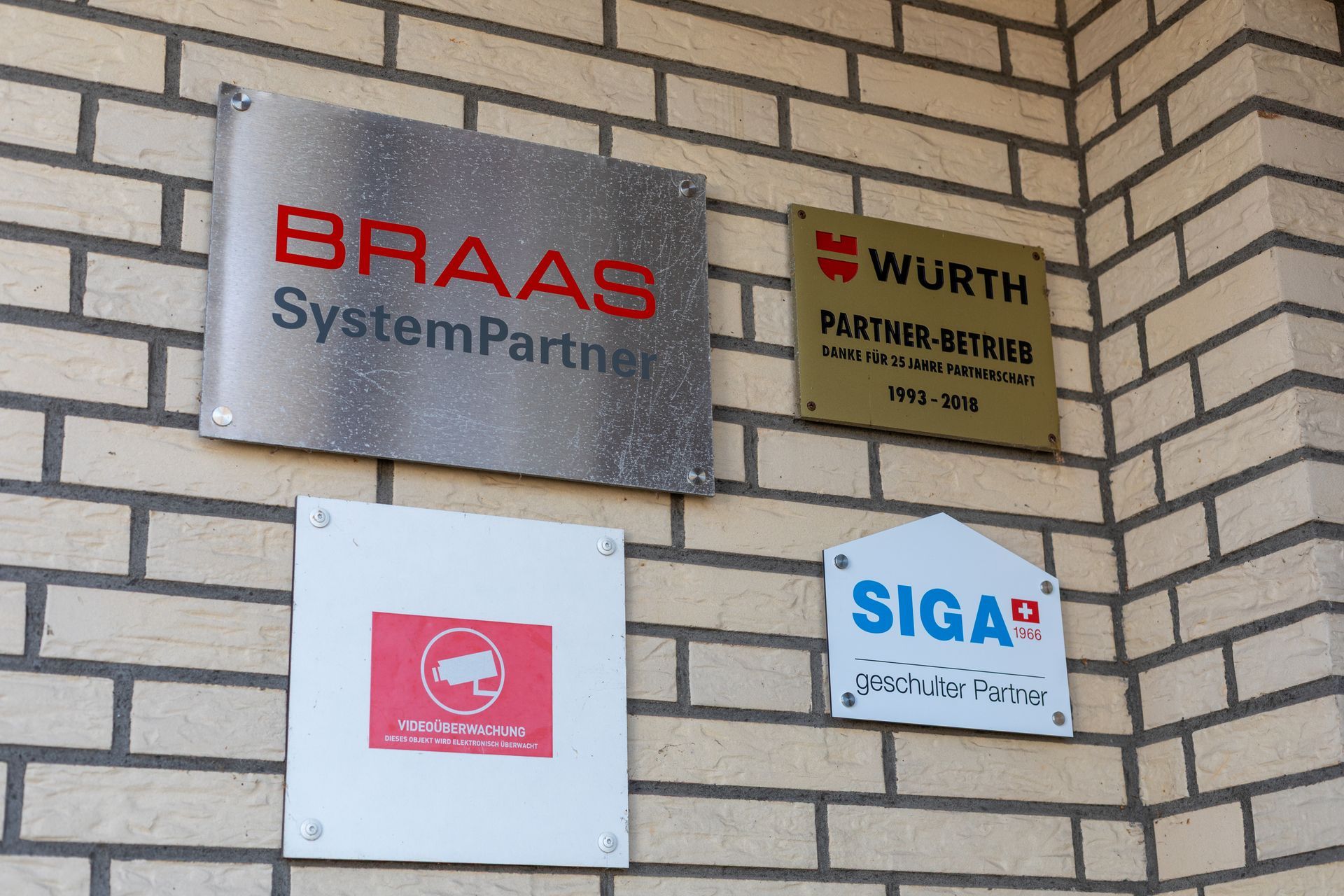 Eine Backsteinmauer mit Schildern für Braas Systempartner und Würth