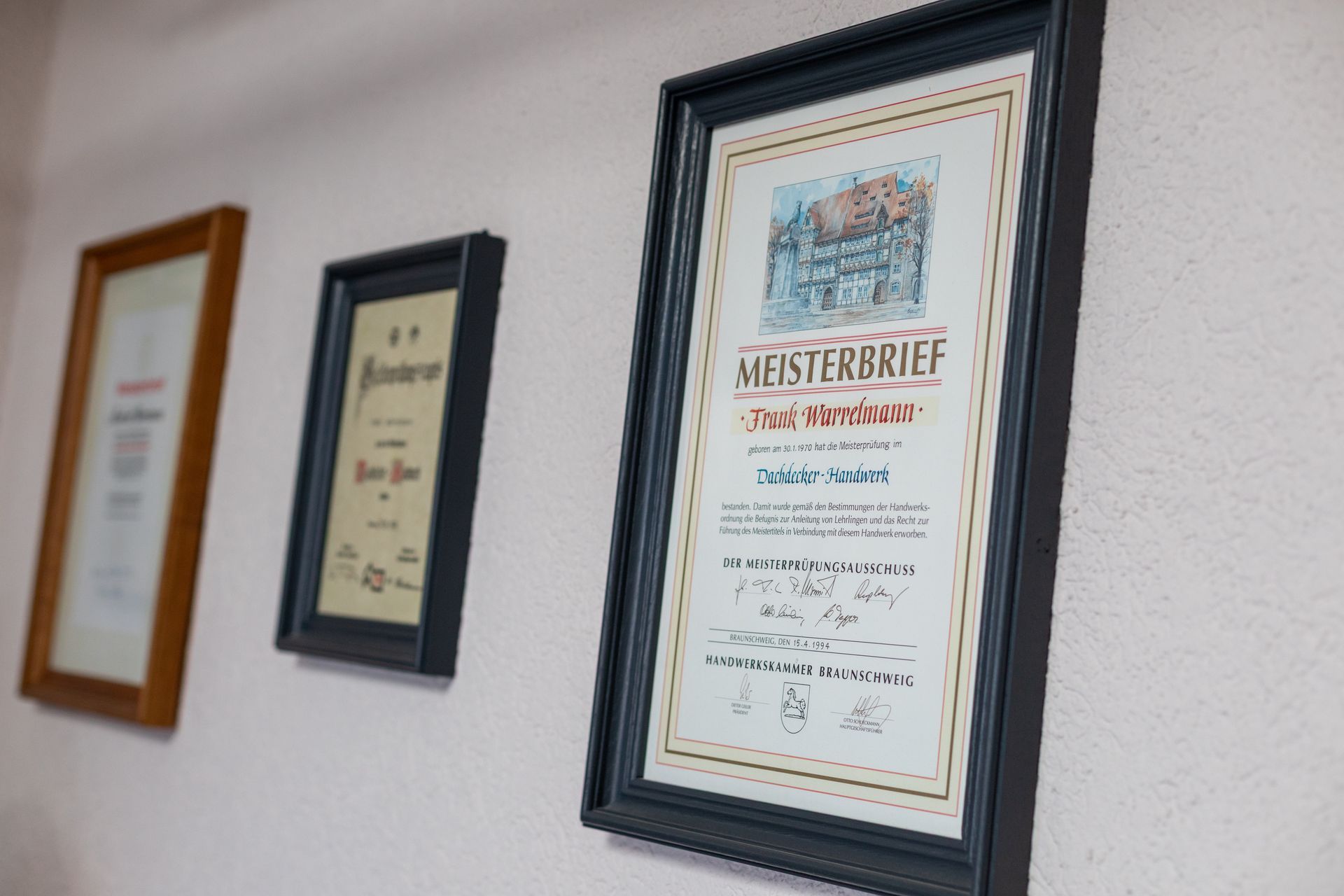 An der Wand hängt neben anderen Zertifikaten ein gerahmtes Zertifikat.