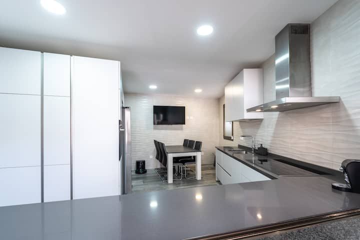 Una cocina con gabinetes blancos, una estufa, una mesa y sillas.