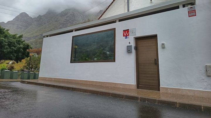 Un edificio blanco con una puerta de madera y una ventana grande.