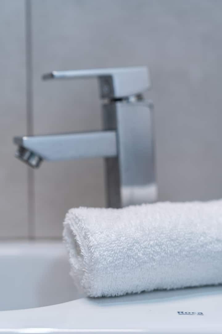 Una toalla está sobre el lavabo del baño, al lado de un grifo.