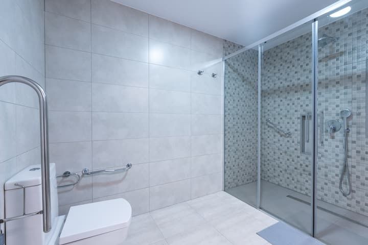 Un baño con inodoro, ducha y puertas corredizas de cristal.