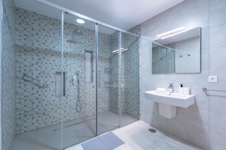 Un baño con ducha, lavabo y espejo.