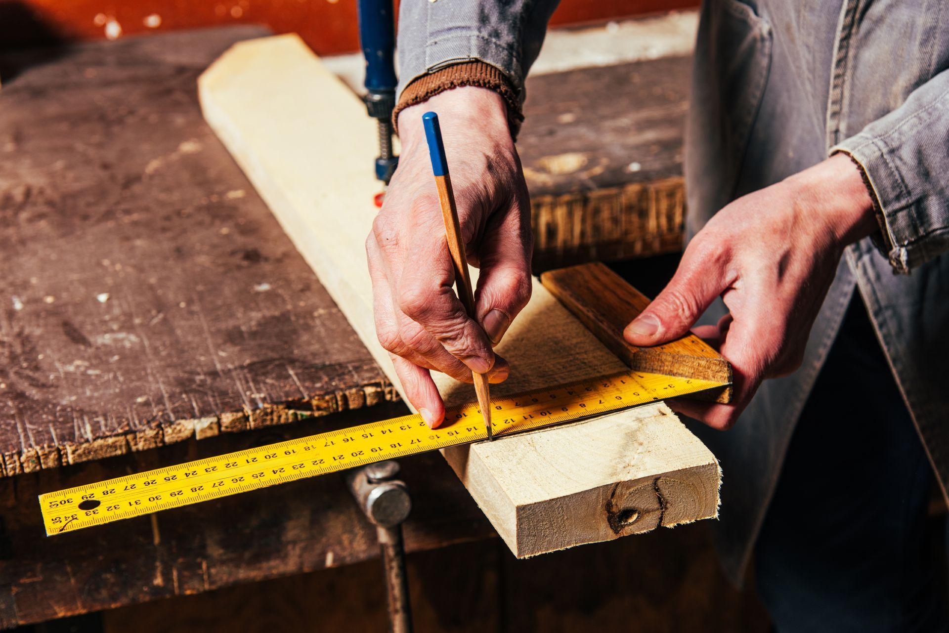 Ein Mann mit Handschuhen arbeitet an einem Stück Holz