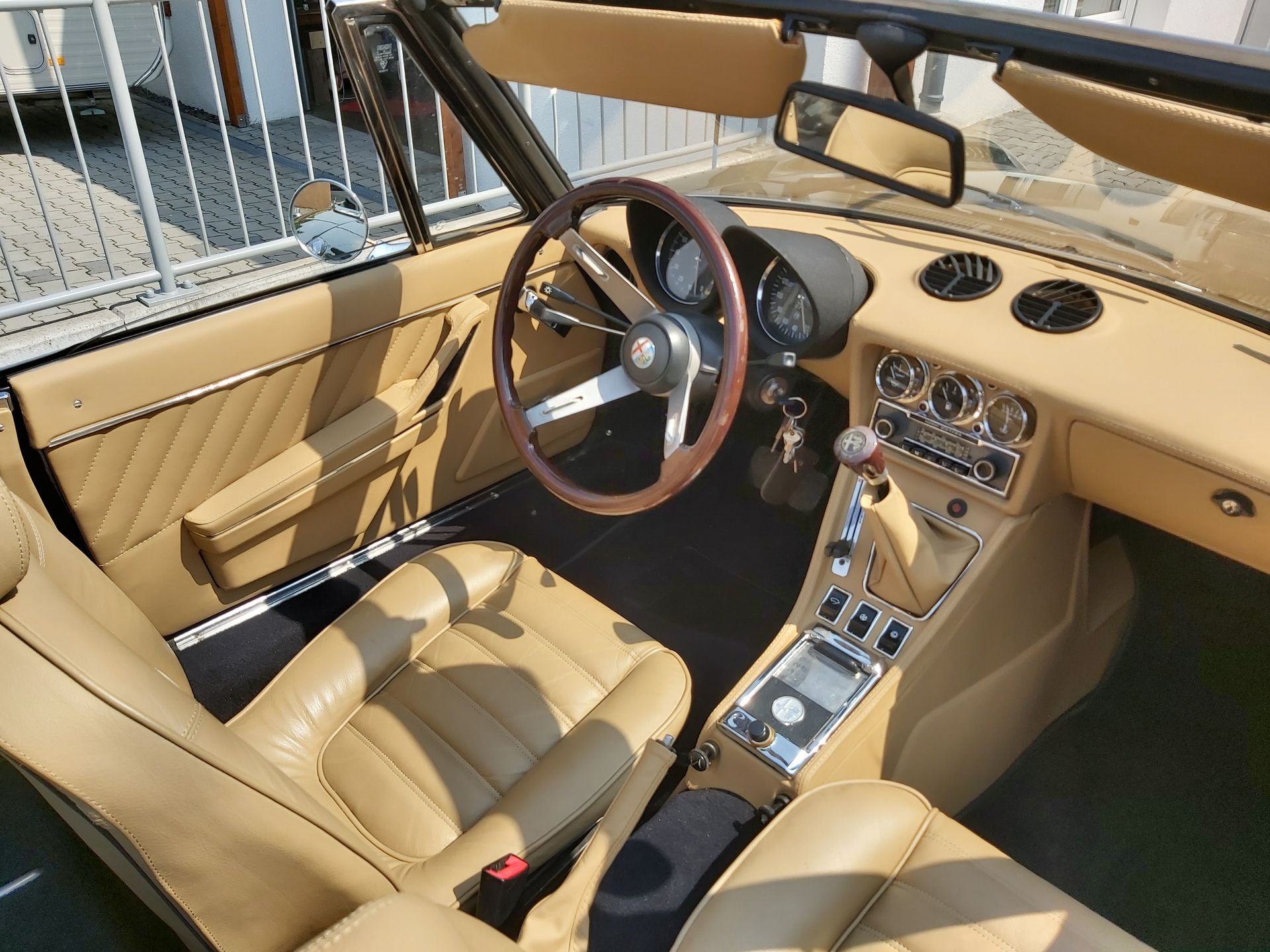 Der Innenraum eines Autos mit hellbraunen Ledersitzen und einem Holzlenkrad