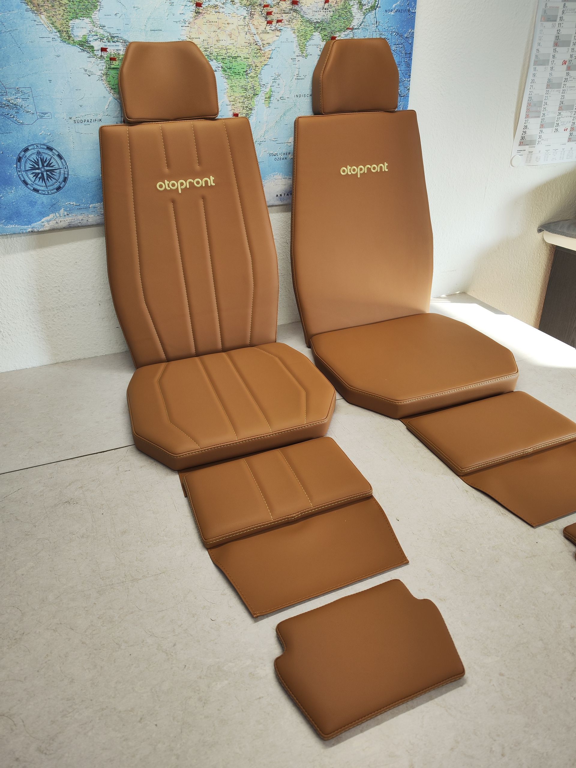 Ein Paar braune Sitzkissen liegen auf einem Tisch vor einer Weltkarte