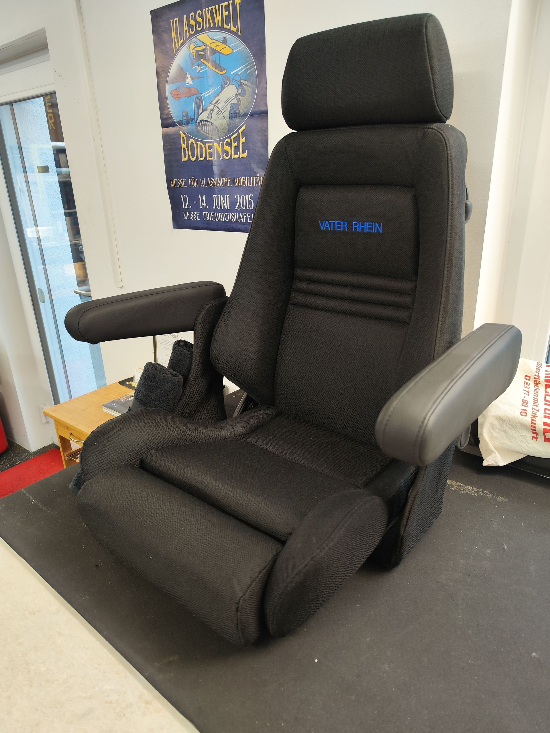 Ein schwarzer Autositz sitzt auf einer Matte vor einem Plakat mit der Aufschrift „Beast“