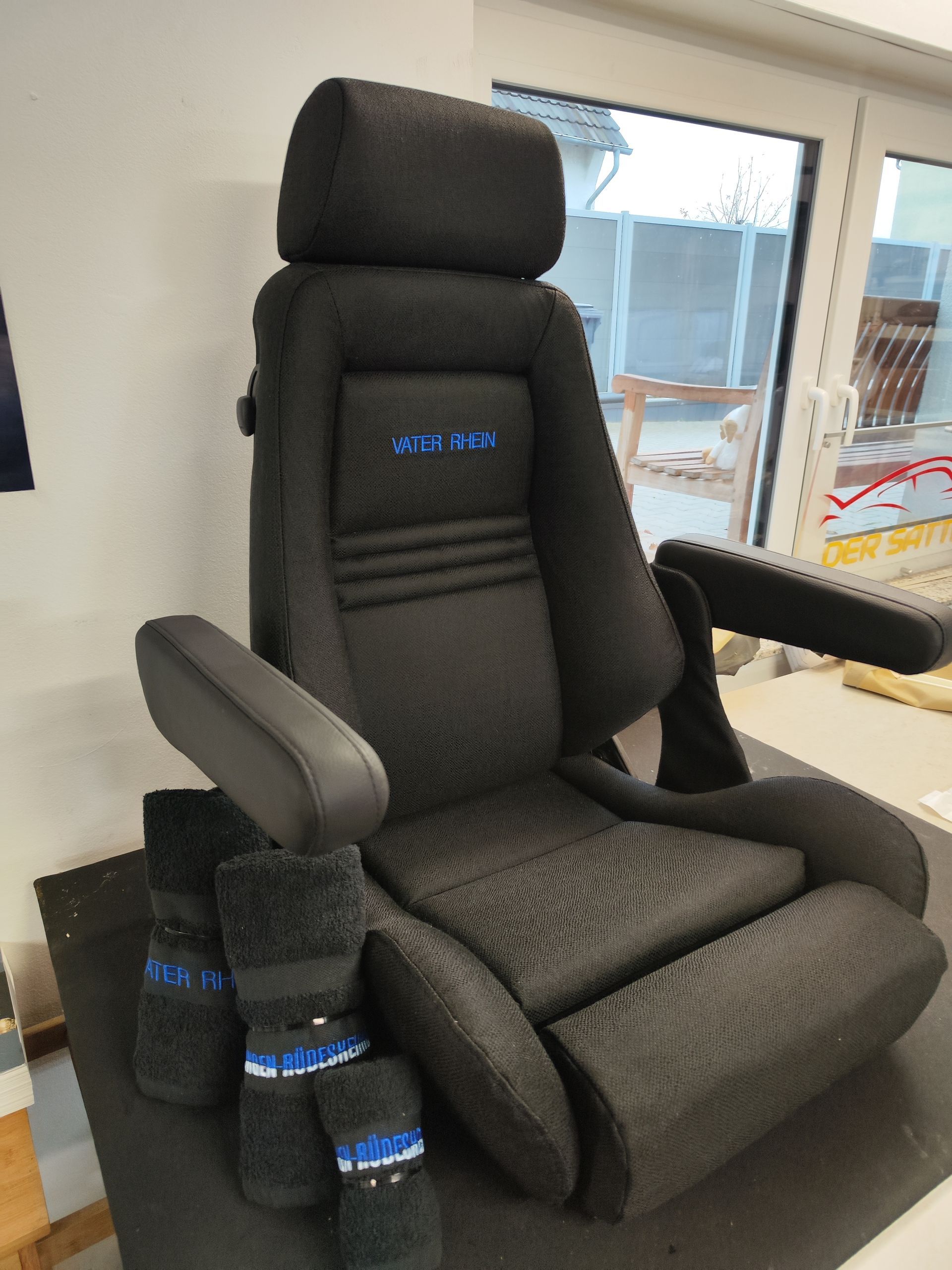 Auf einem Tisch neben einem Fenster steht ein schwarzer Autositz.
