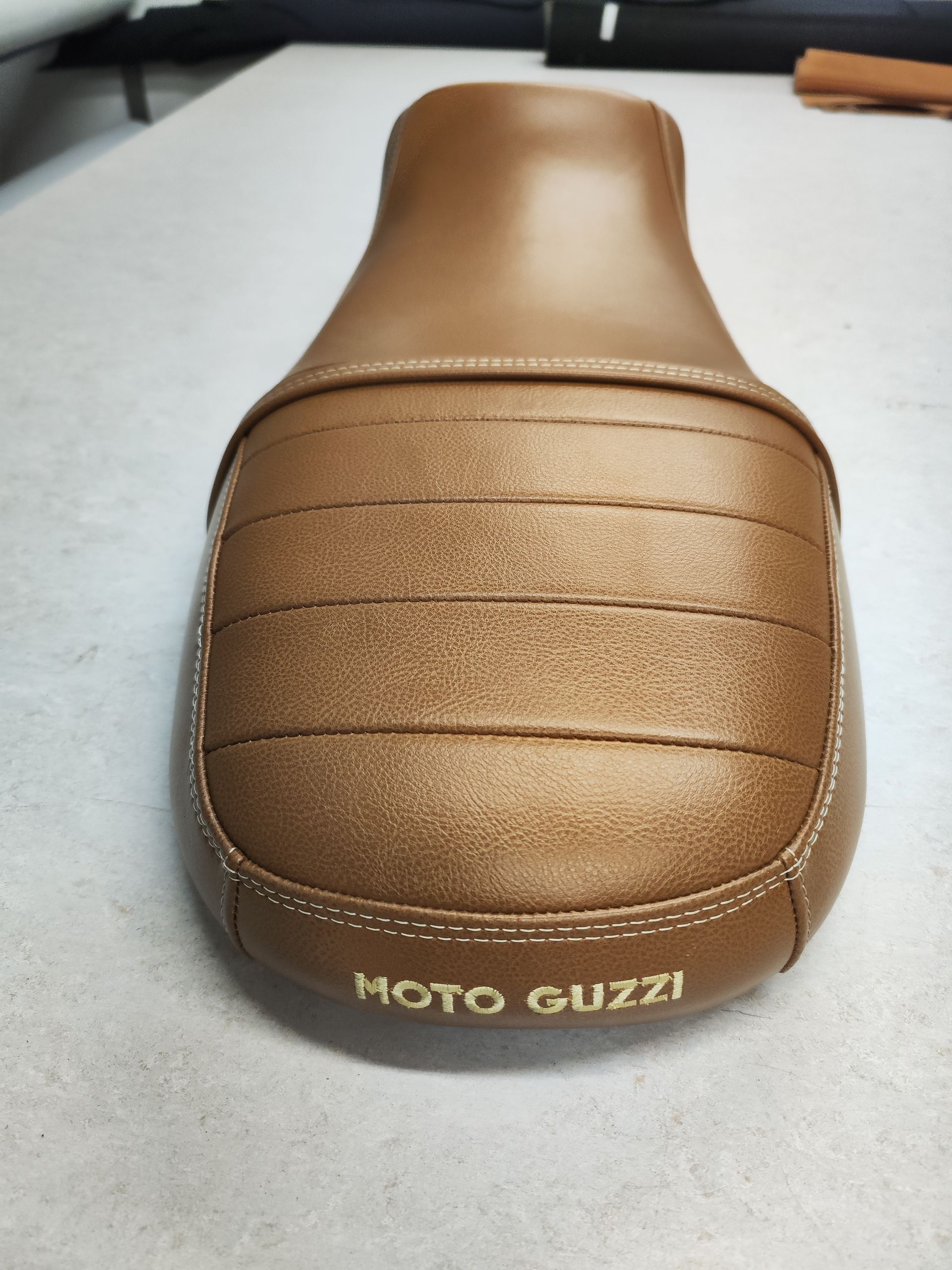 Ein brauner Moto Guzzi Sitz sitzt auf einer weißen Oberfläche