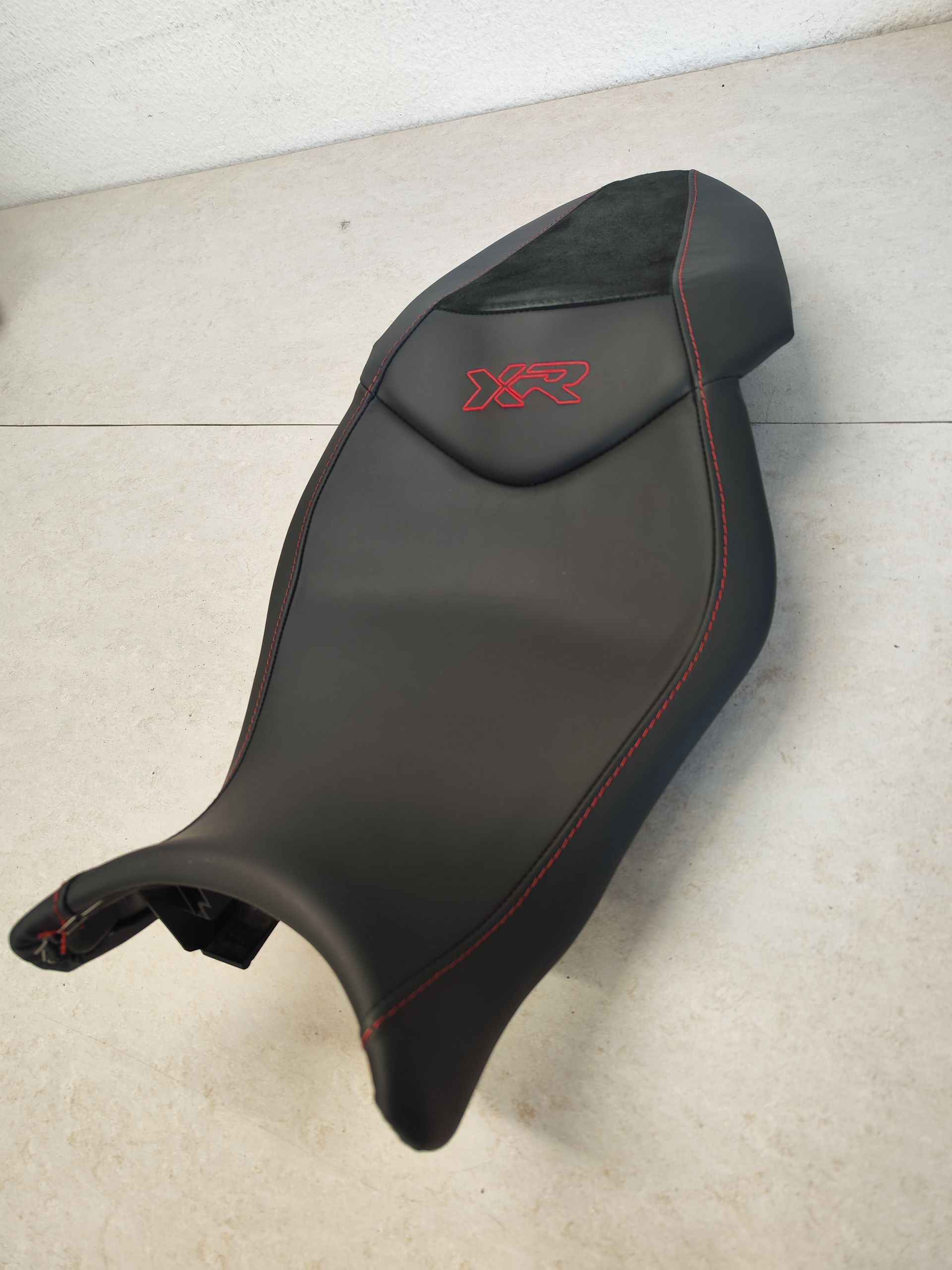Ein schwarzer Motorradsitz mit roten Nähten