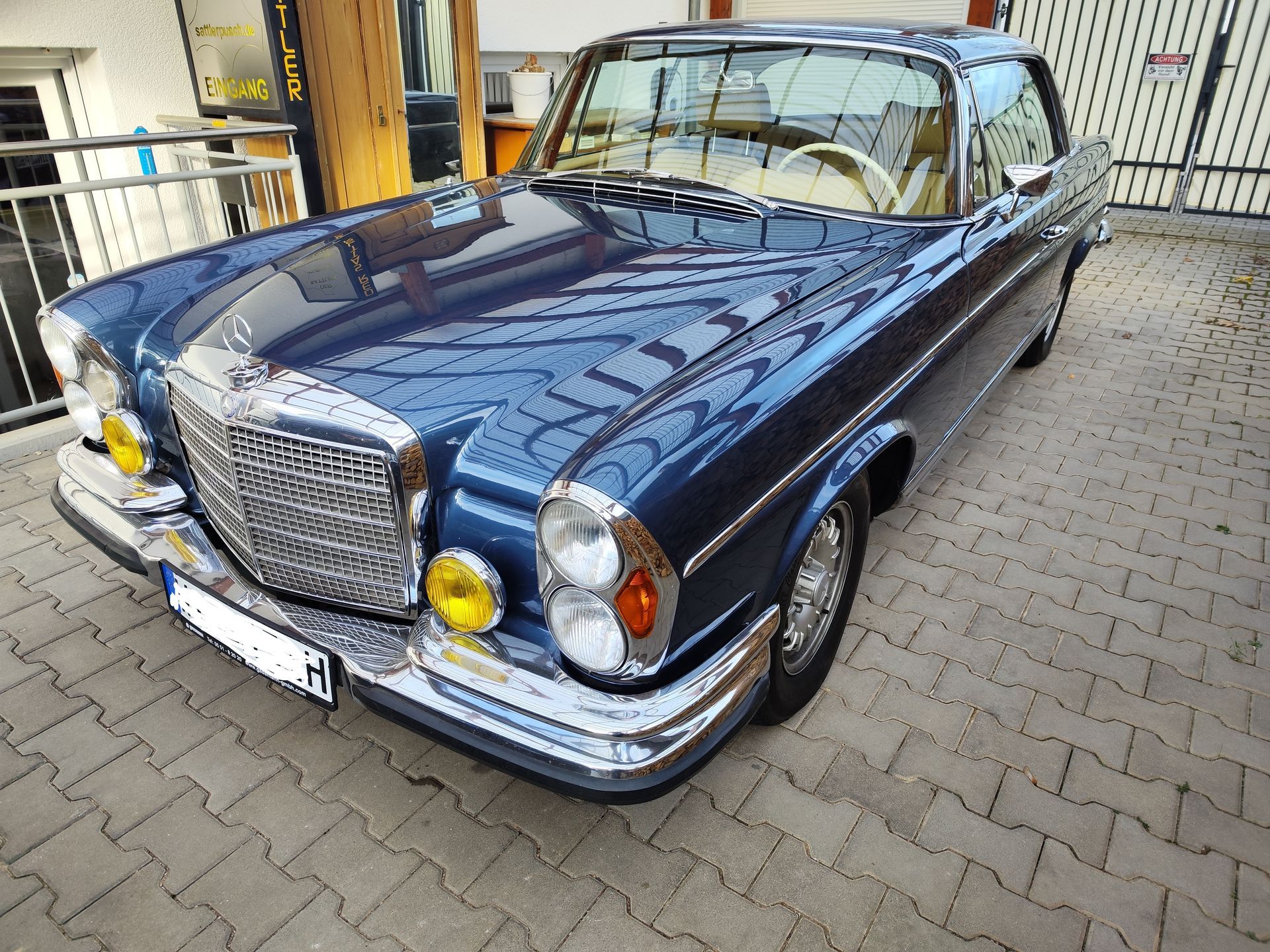 Ein blauer Mercedes Benz steht auf einer gepflasterten Auffahrt