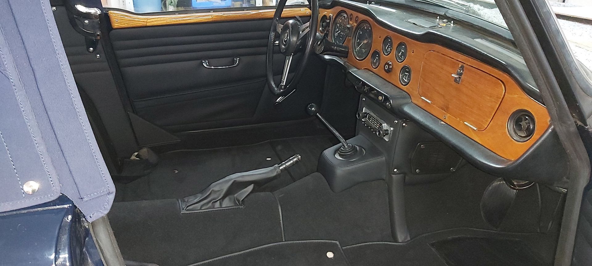 Der Innenraum eines schwarzen Autos mit einem Armaturenbrett aus Holz.