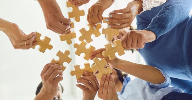Varias personas sujetando fichas de puzzle de madera