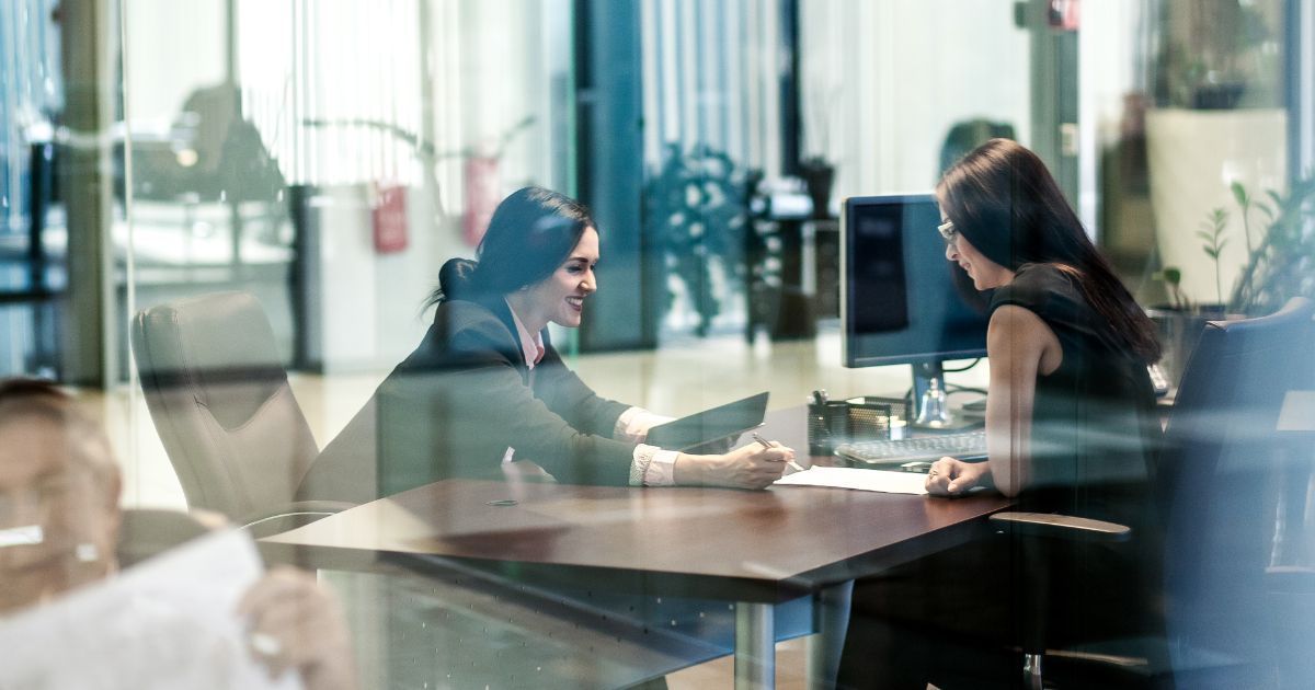 Dos mujeres en una sala de reuniones leyendo un documento