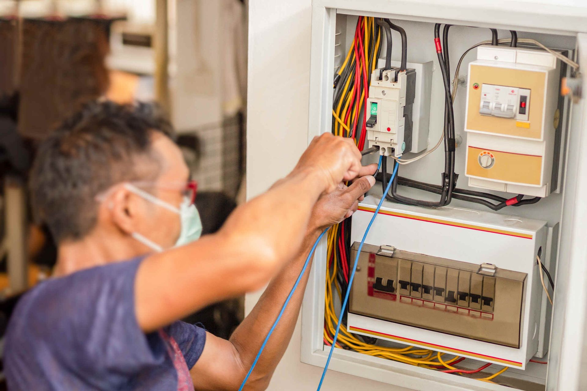 Un hombre que lleva una máscara está trabajando en una caja eléctrica.