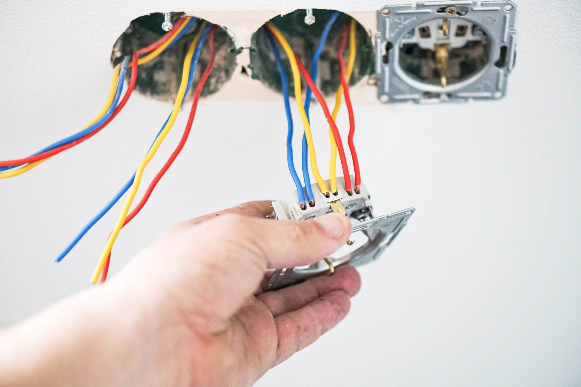 Una persona está instalando una toma de corriente eléctrica en una pared.
