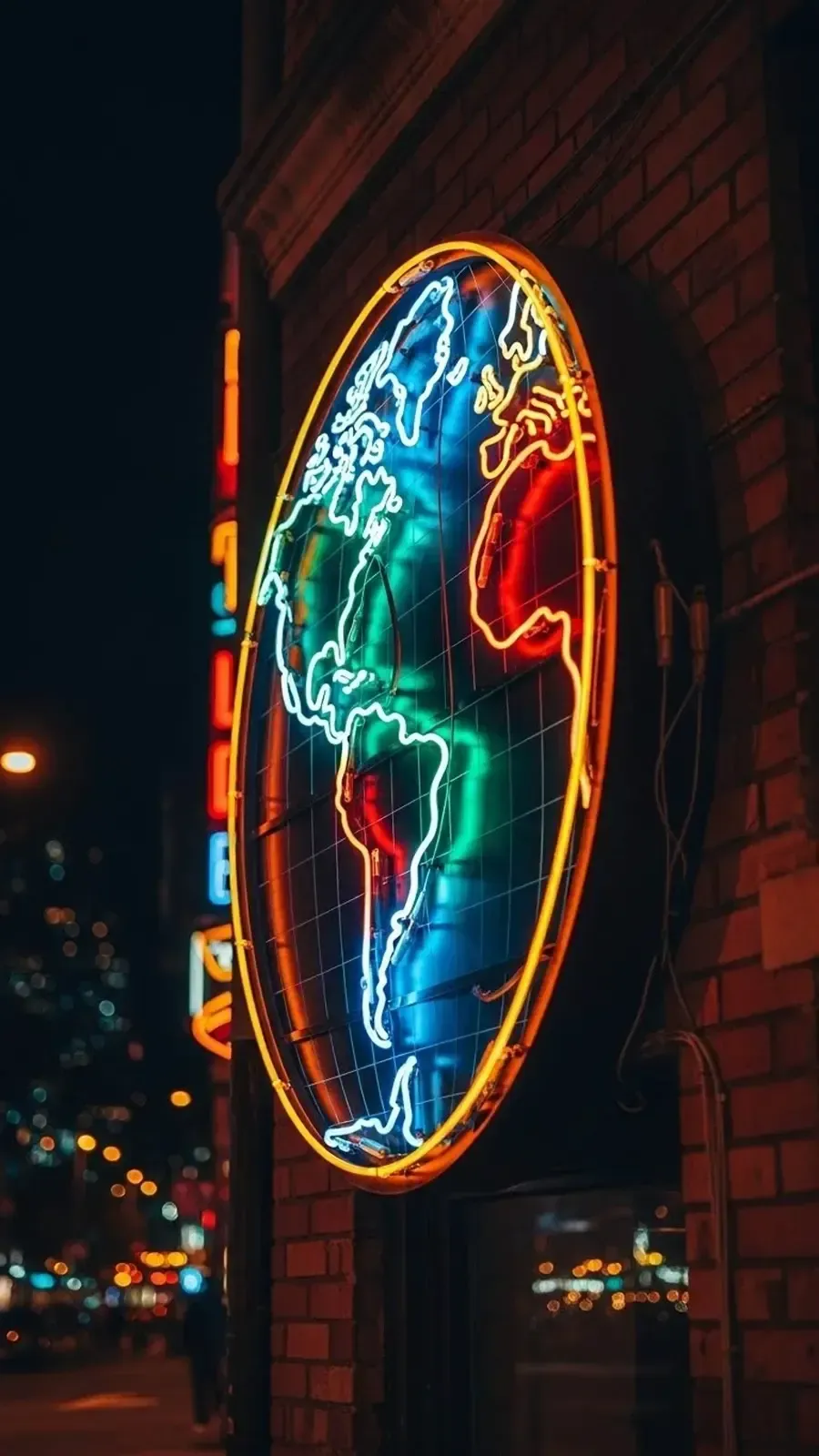 Un letrero de neón con forma de globo terráqueo que brilla en azul, rojo y amarillo sobre una pared de ladrillos.