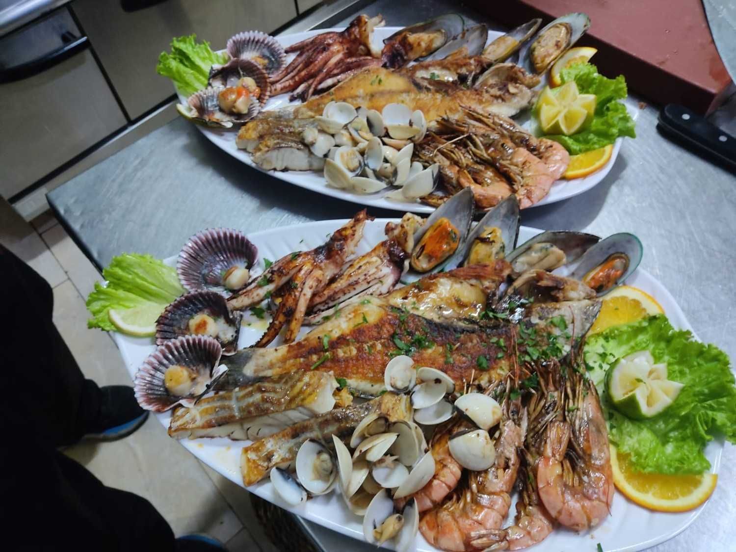Dos platos de mariscos a la parrilla, que incluyen camarones, mejillones, pescado, almejas y vieiras.