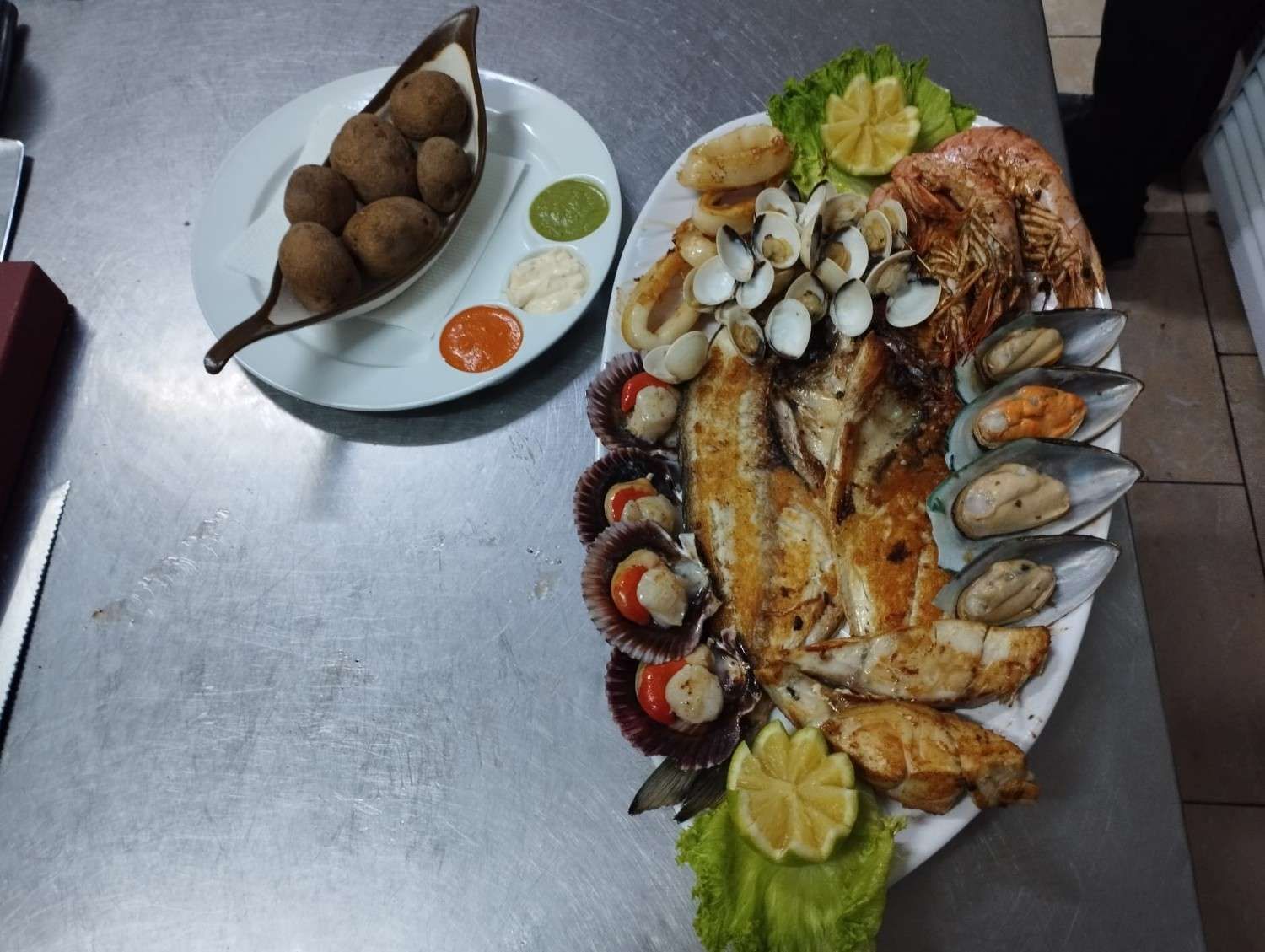 Plato de mariscos con almejas, pescado, vieiras, mejillones y camarones, además de bolas fritas y salsas para mojar.